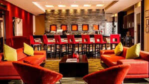A modern lobby with red sofas, a bar area, and a stone wall. - Southern Sun Newlands (Cape Town)