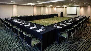 Une salle de conférence équipée d’une longue table, de chaises et d’un écran de projection.
