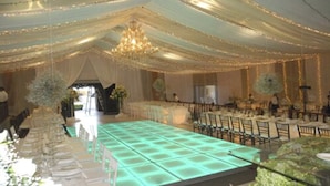 Une salle de banquet avec une longue table, des chaises et des rideaux tombants.
