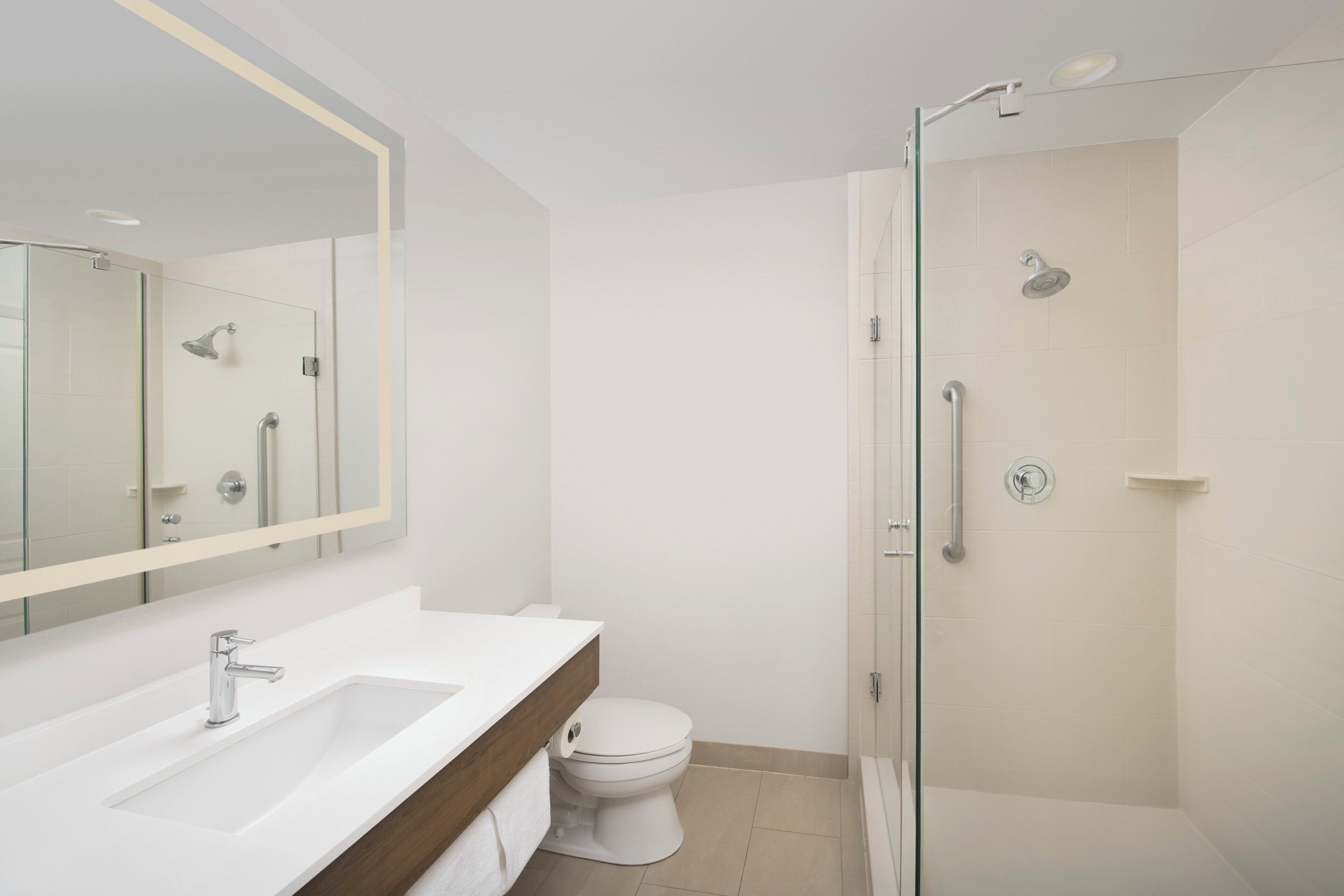 A modern bathroom with a glass-enclosed shower, a white sink, and a toilet.