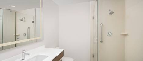 A modern bathroom with a glass-enclosed shower, a white sink, and a toilet.
