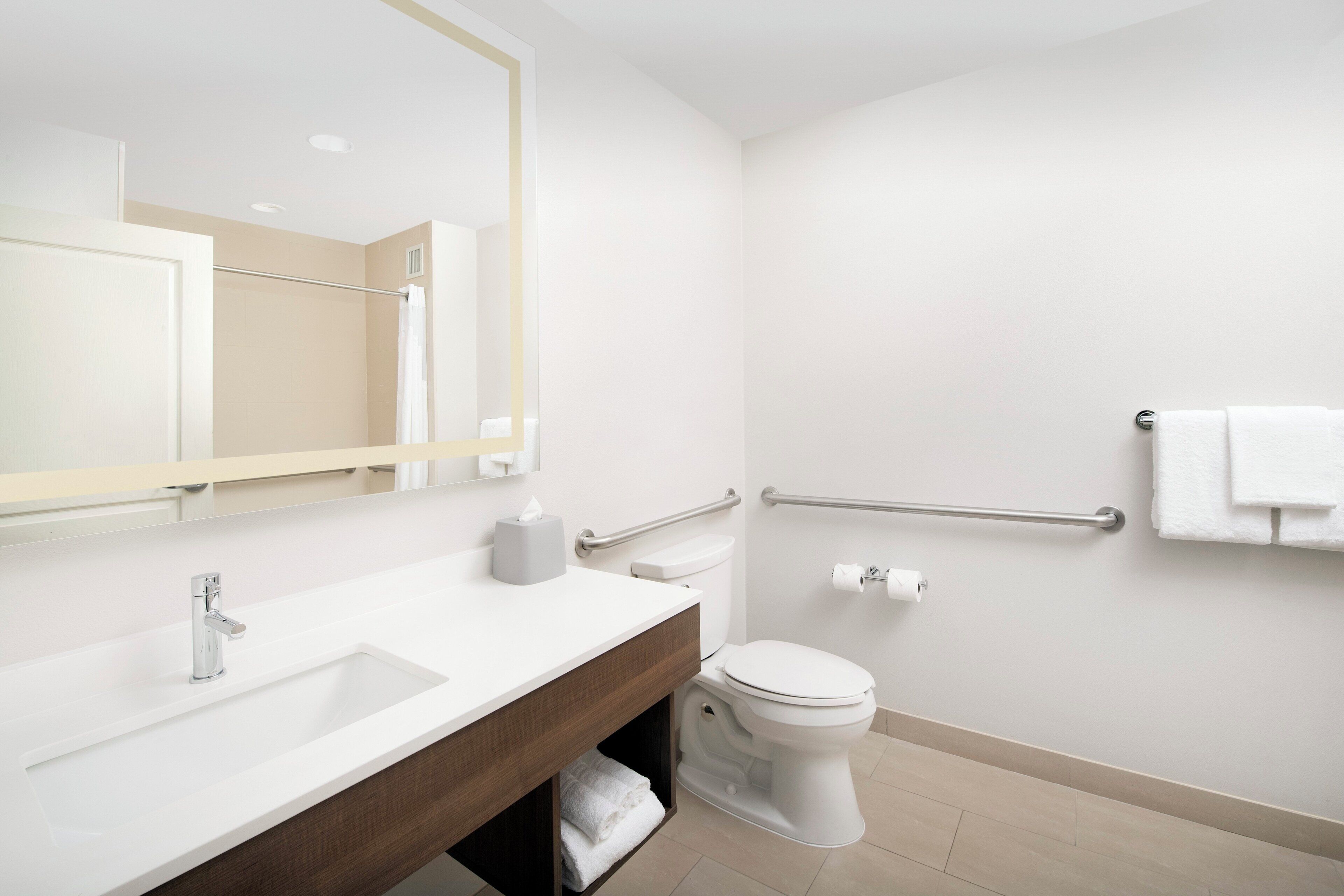 A modern bathroom with a white sink, mirror, and toilet.