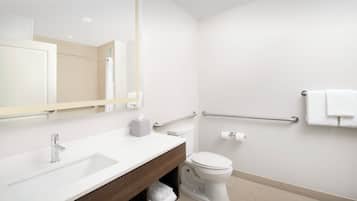A modern bathroom with a white sink, mirror, and toilet.