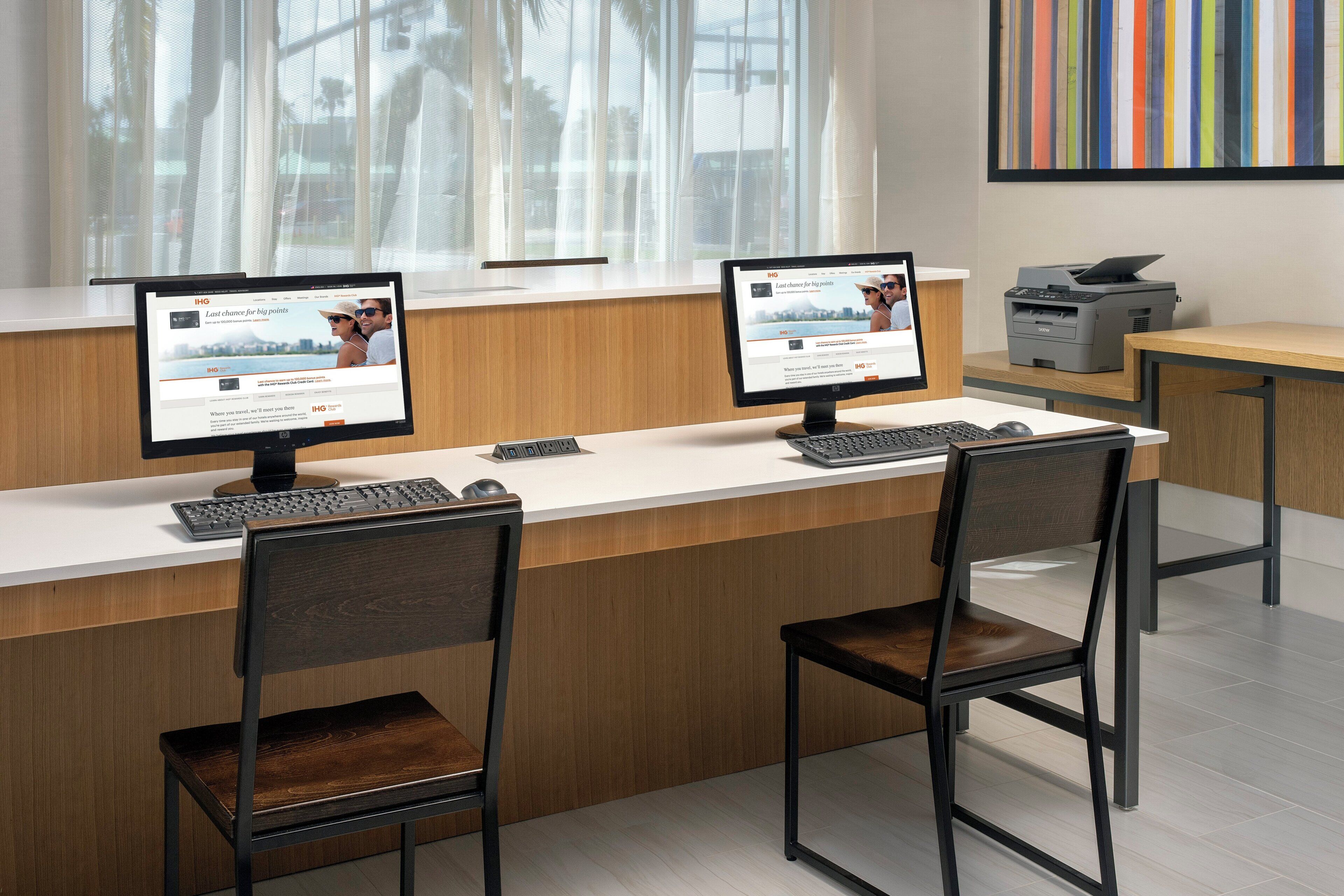 A reception desk with two computer monitors, a keyboard, and two chairs.