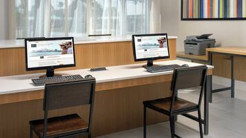 A reception desk with two computer monitors, a keyboard, and two chairs.