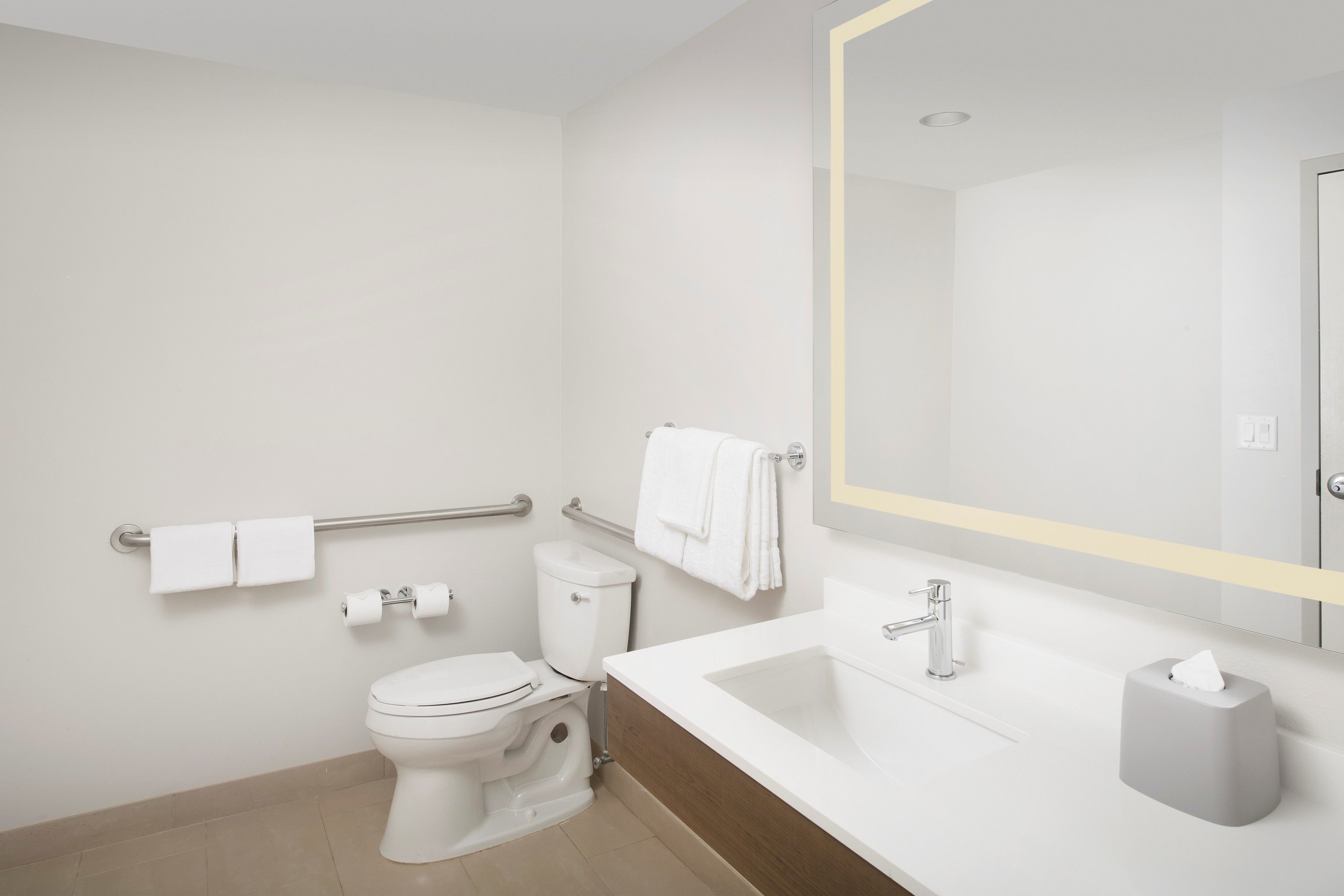 A modern bathroom with a toilet, bidet, sink, and mirror.