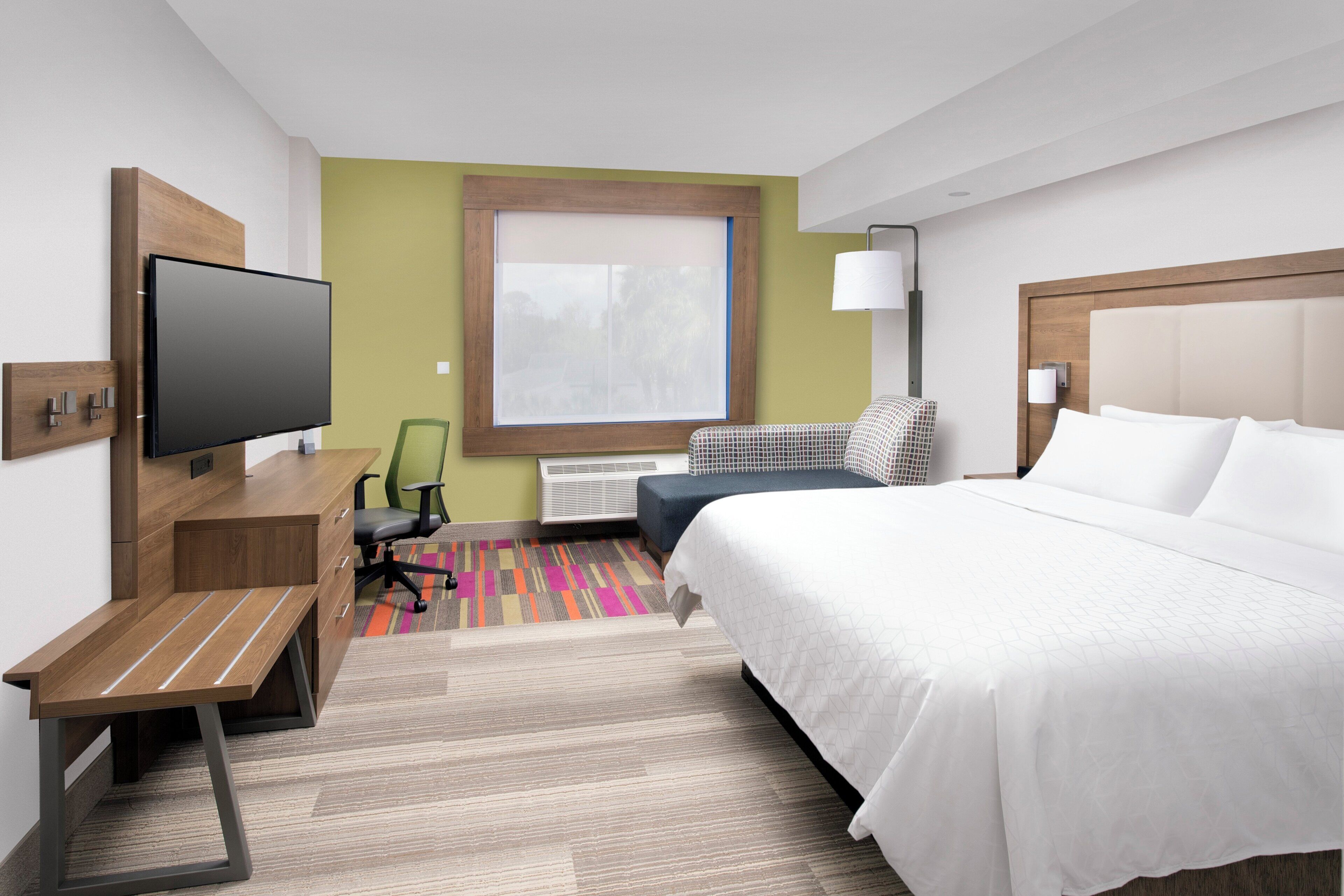 Une chambre d’hôtel équipée d’un lit, d’un bureau, d’une chaise, d’une télévision, d’une fenêtre et d’une lampe.