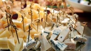 Eine Platte mit Käsewürfeln und Zahnstochern, einige davon Blauschimmelkäse, andere gelber Käse, auf einer reflektierenden Fläche angerichtet.