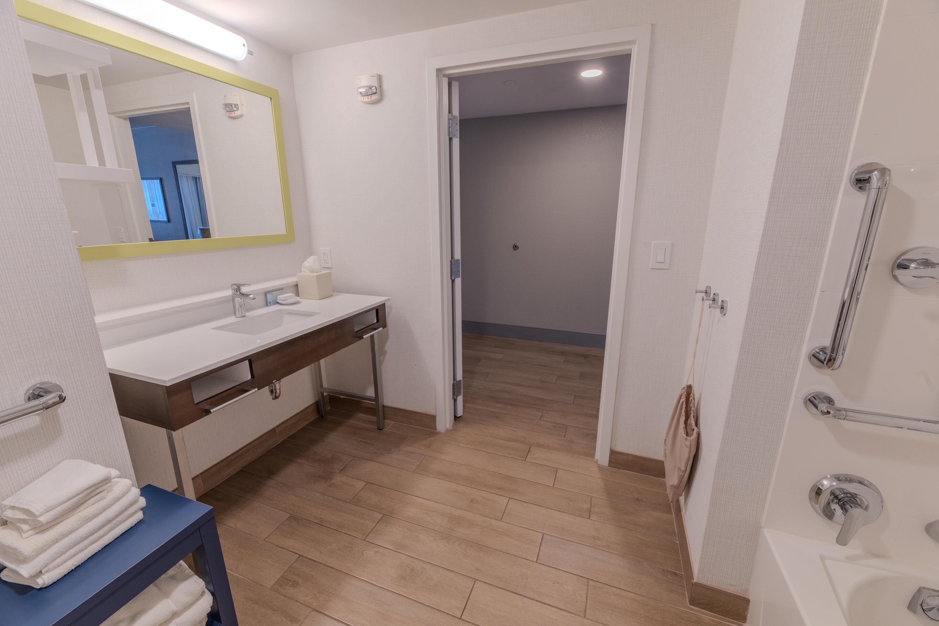 A modern bathroom with a white sink, mirror, and shower area.