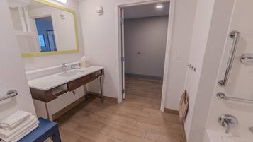 A modern bathroom with a white sink, mirror, and shower area.