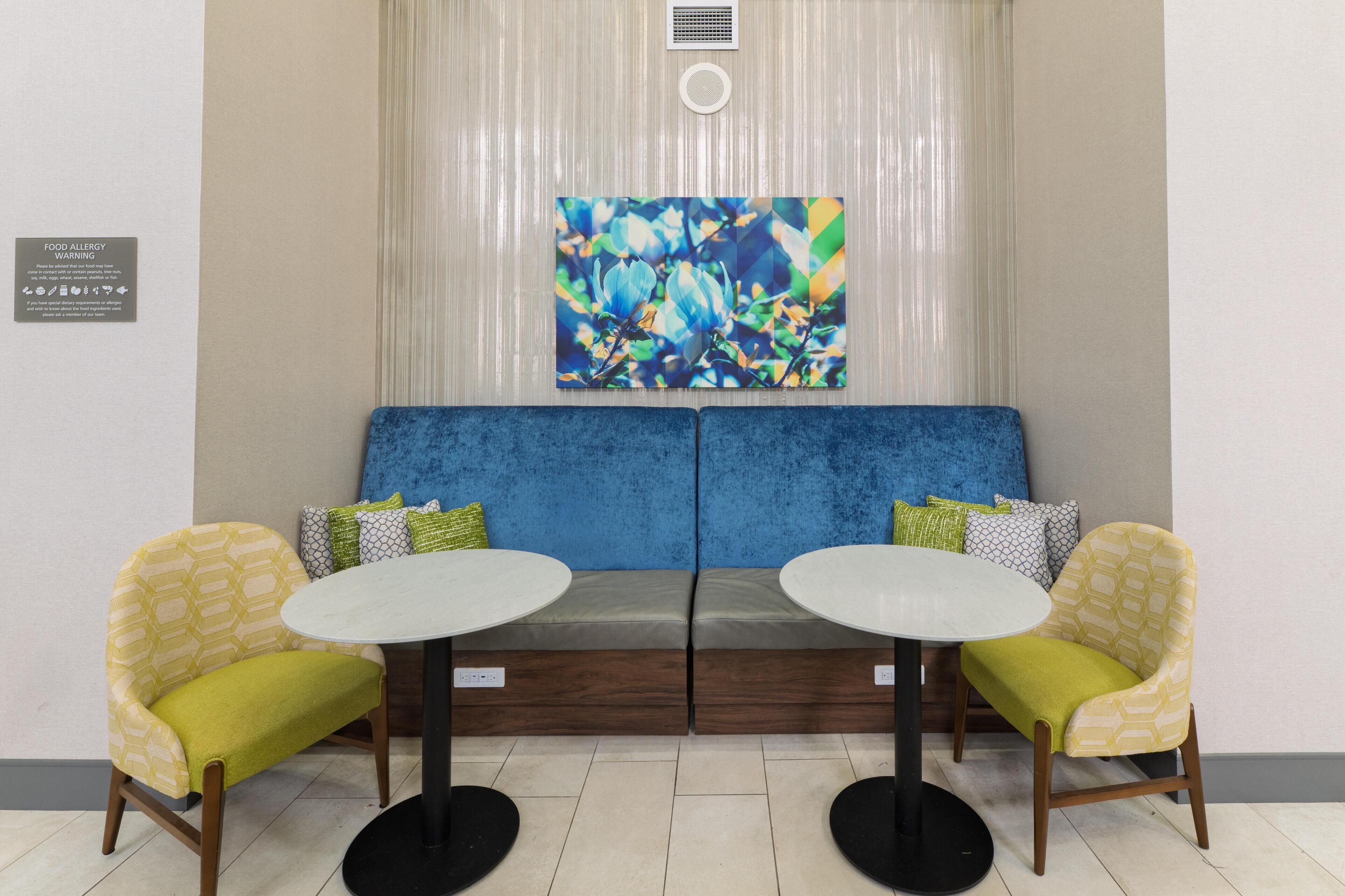A seating area with a blue sofa, two yellow chairs, and a round table.