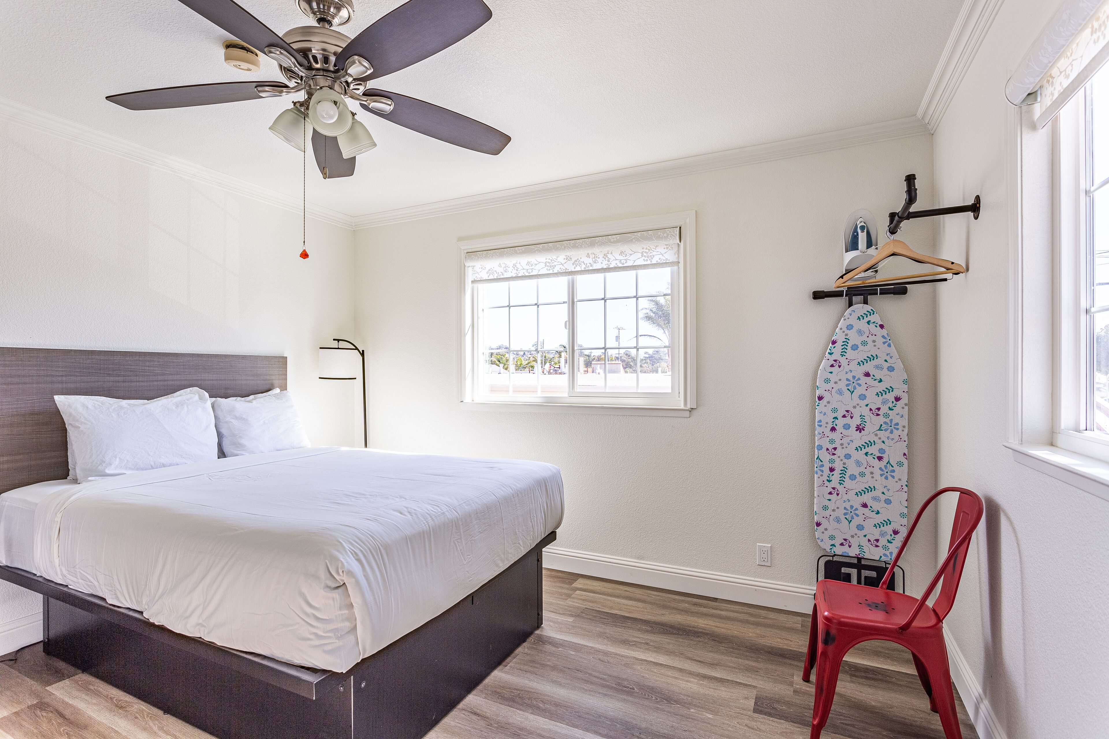 A bedroom with a bed, a ceiling fan, a window with a view, and a red chair.