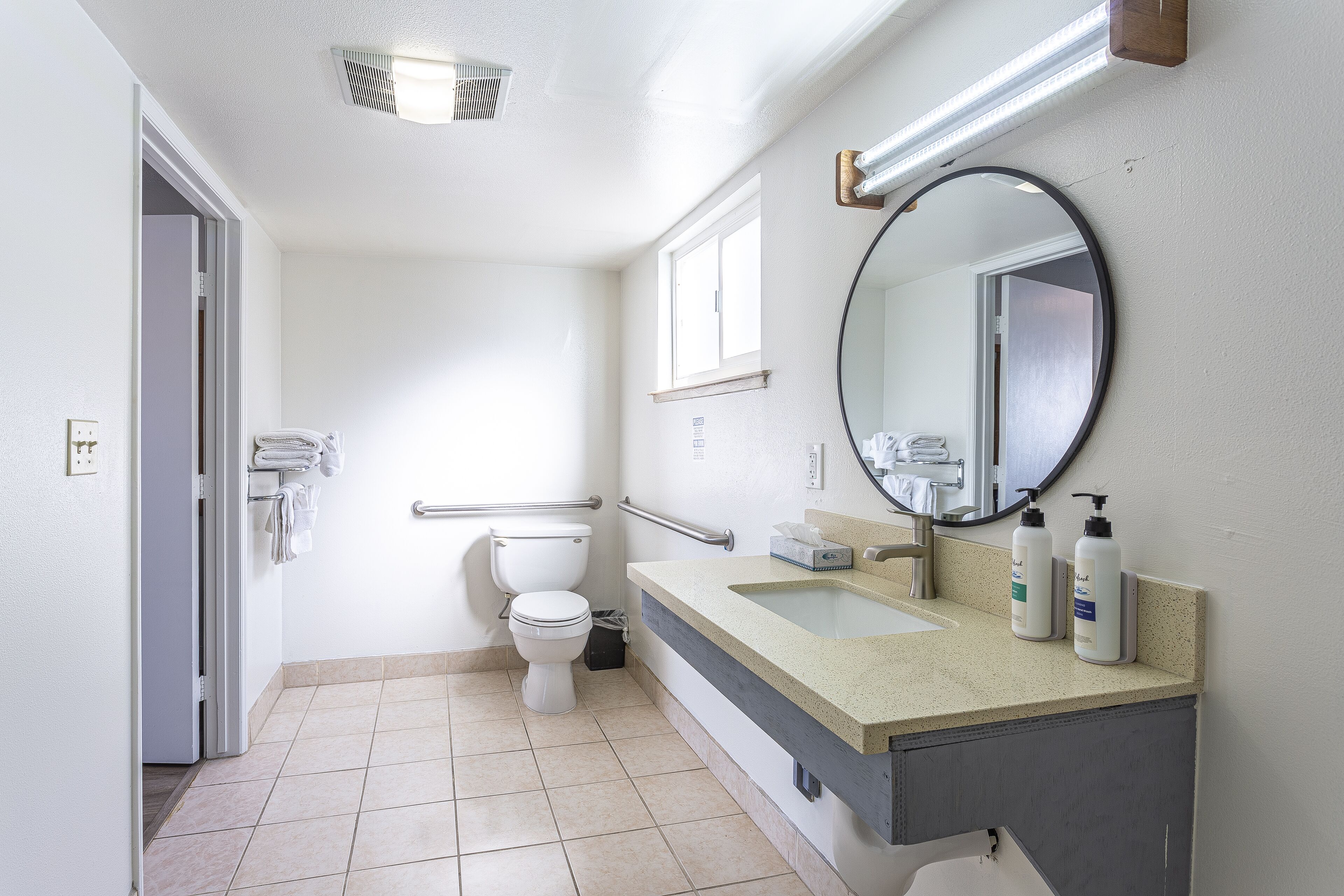 Un baño moderno con inodoro, lavamanos y espejo.