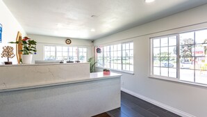 A reception area with a marble counter, large windows, and a view of the street. - Coastal Breeze Inn (Morro Bay)