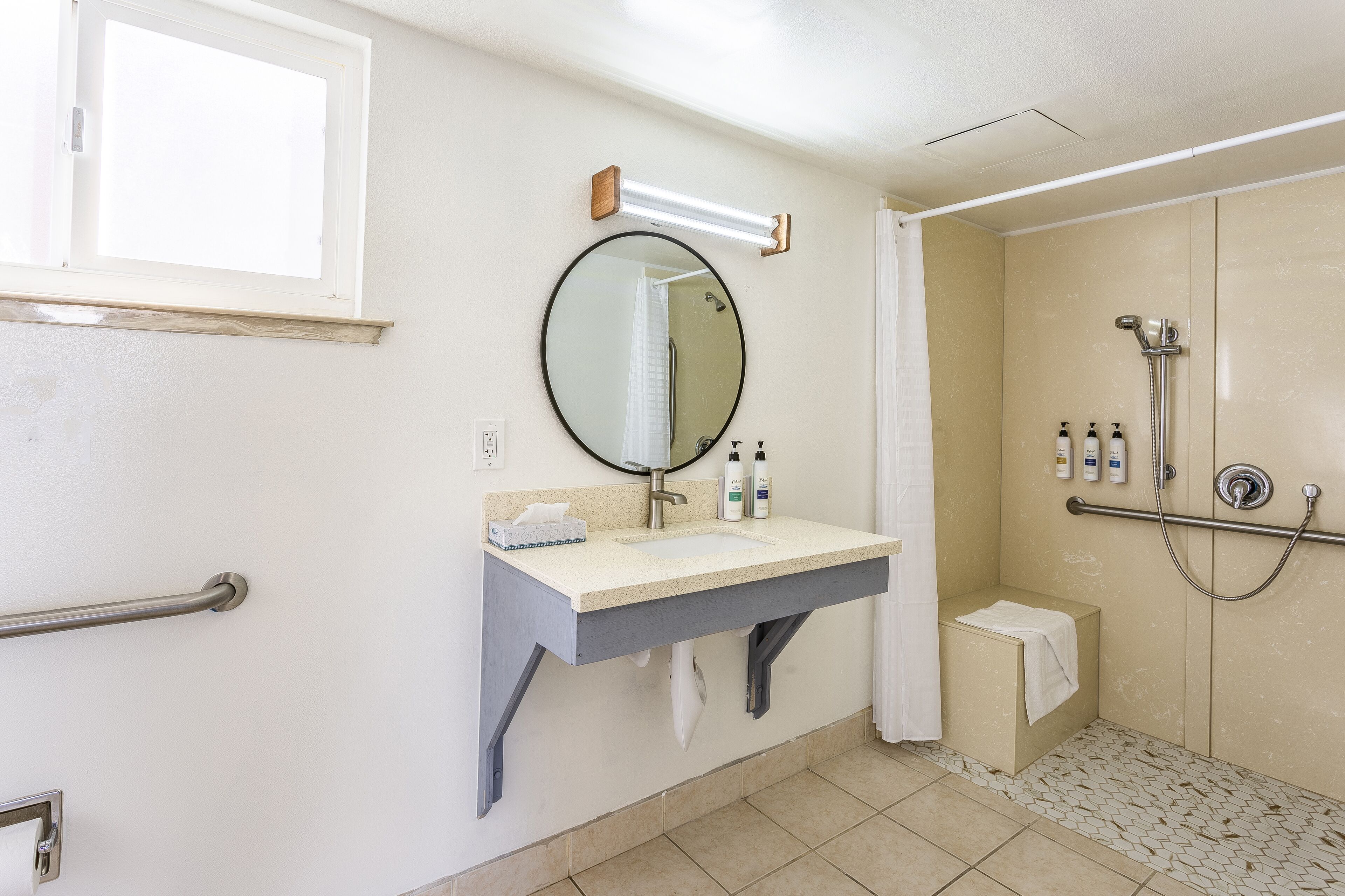 A bathroom with a sink, mirror, and shower.