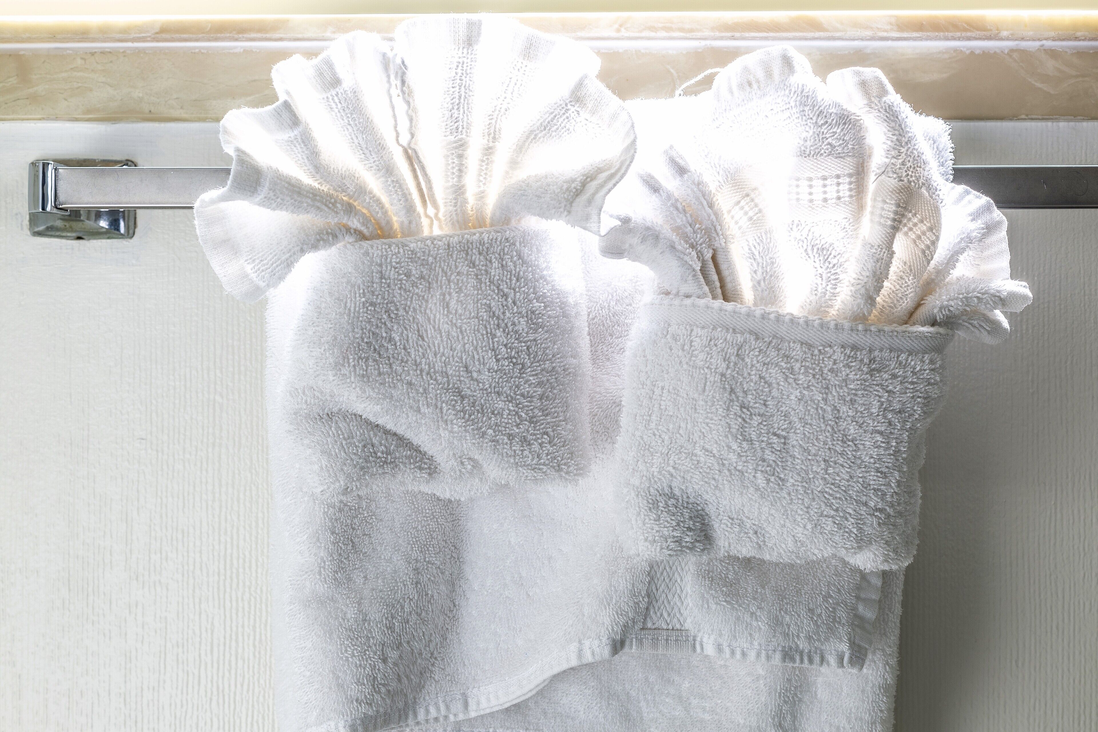 A bathroom with a towel rack holding two white towels.