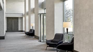 En rummelig lobby med et mønstret tæppe, store vinduer og moderne siddeområder.