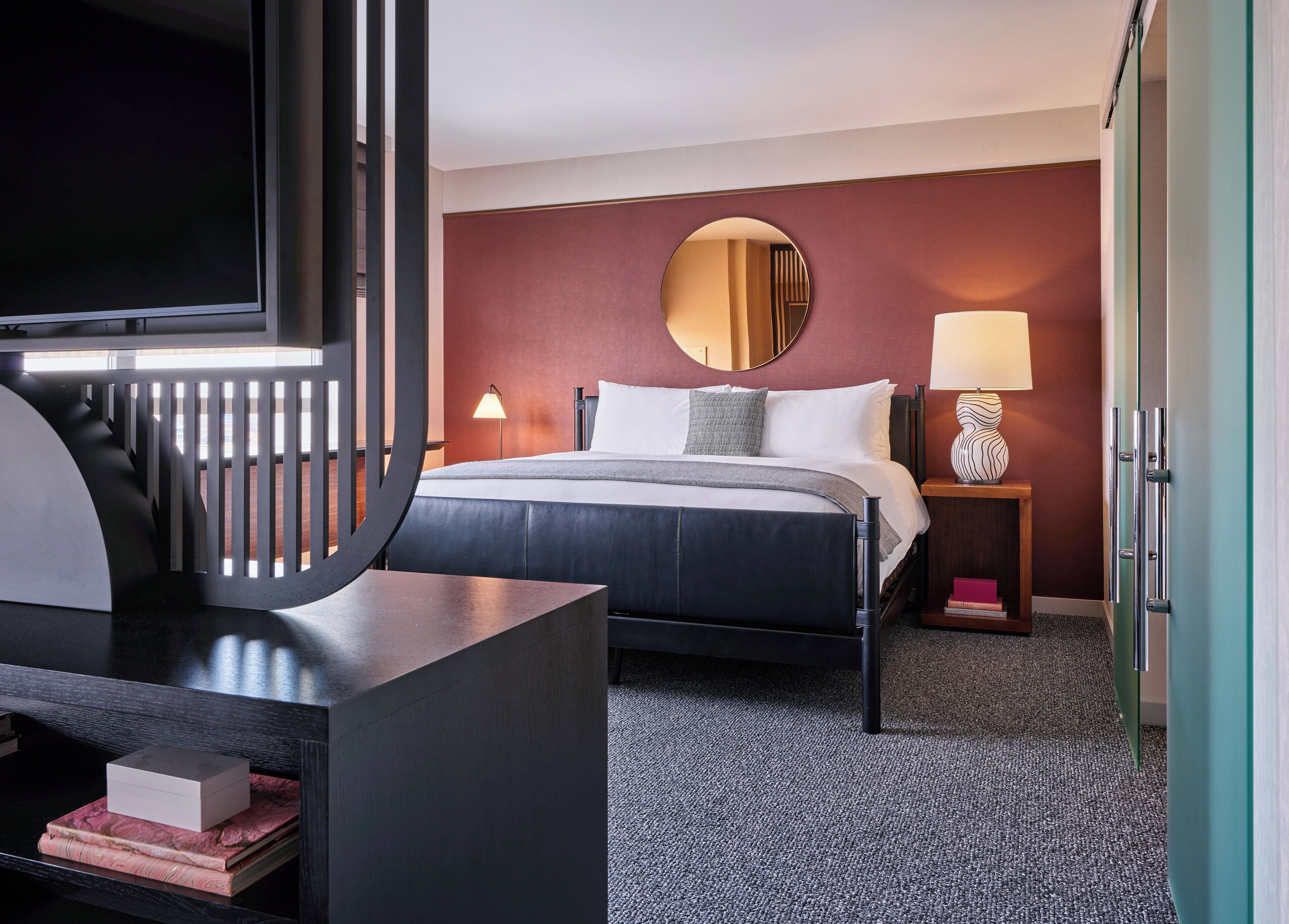 A hotel room with a bed, a TV, a desk, a lamp, and a wardrobe.