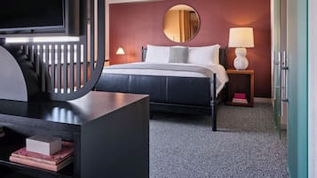 A hotel room with a bed, a TV, a desk, a lamp, and a wardrobe.