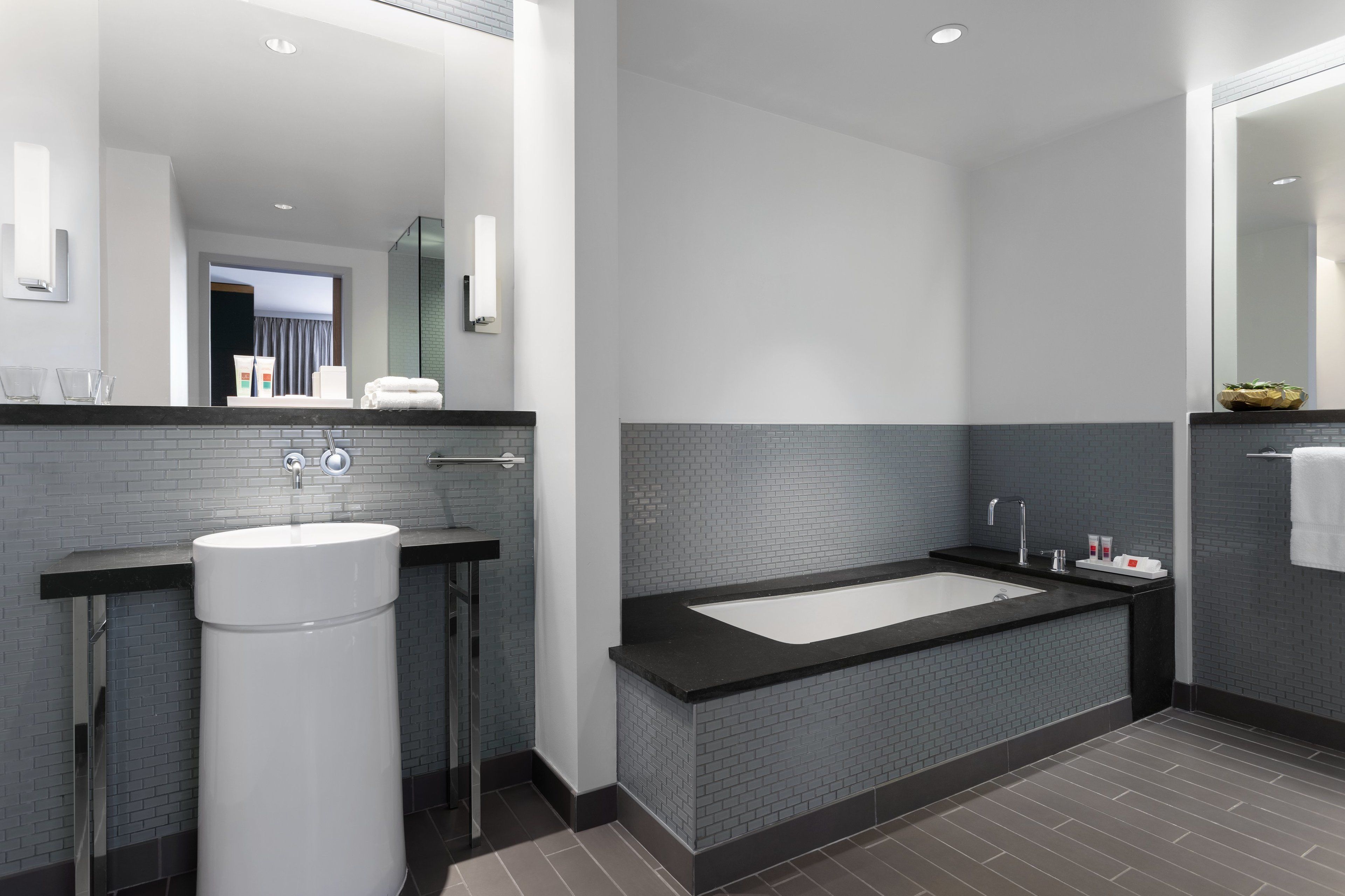 A modern bathroom with a large bathtub, a white sink, and a mirror.