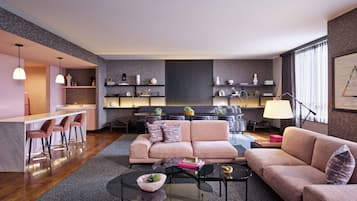 A modern living room with a sofa, coffee table, and bar area with stools.