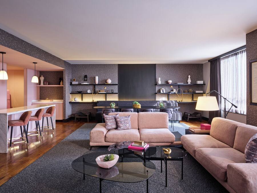 A modern living room with a sofa, coffee table, and bar area with stools.