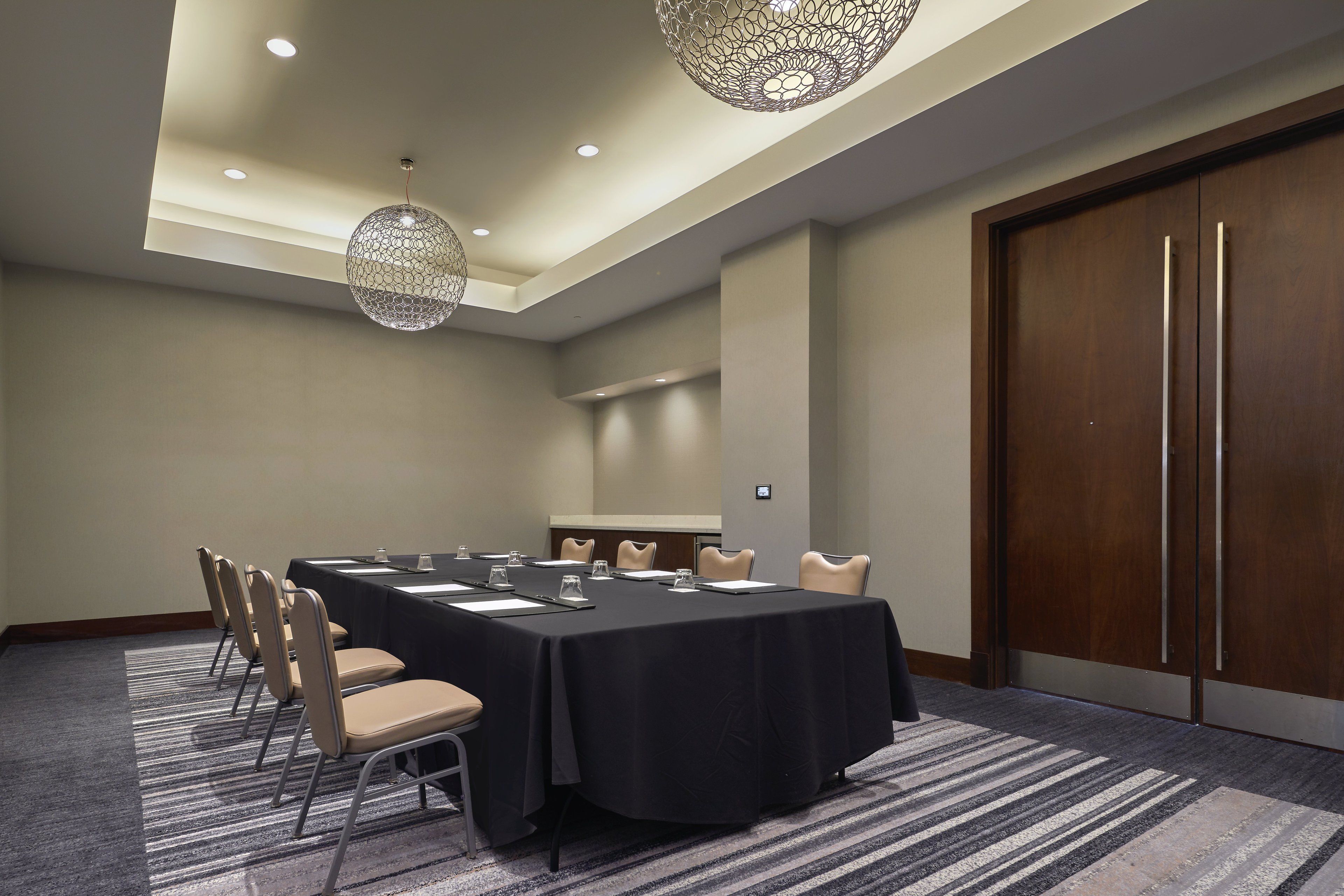A conference room with a long table, chairs, and a large wooden door.