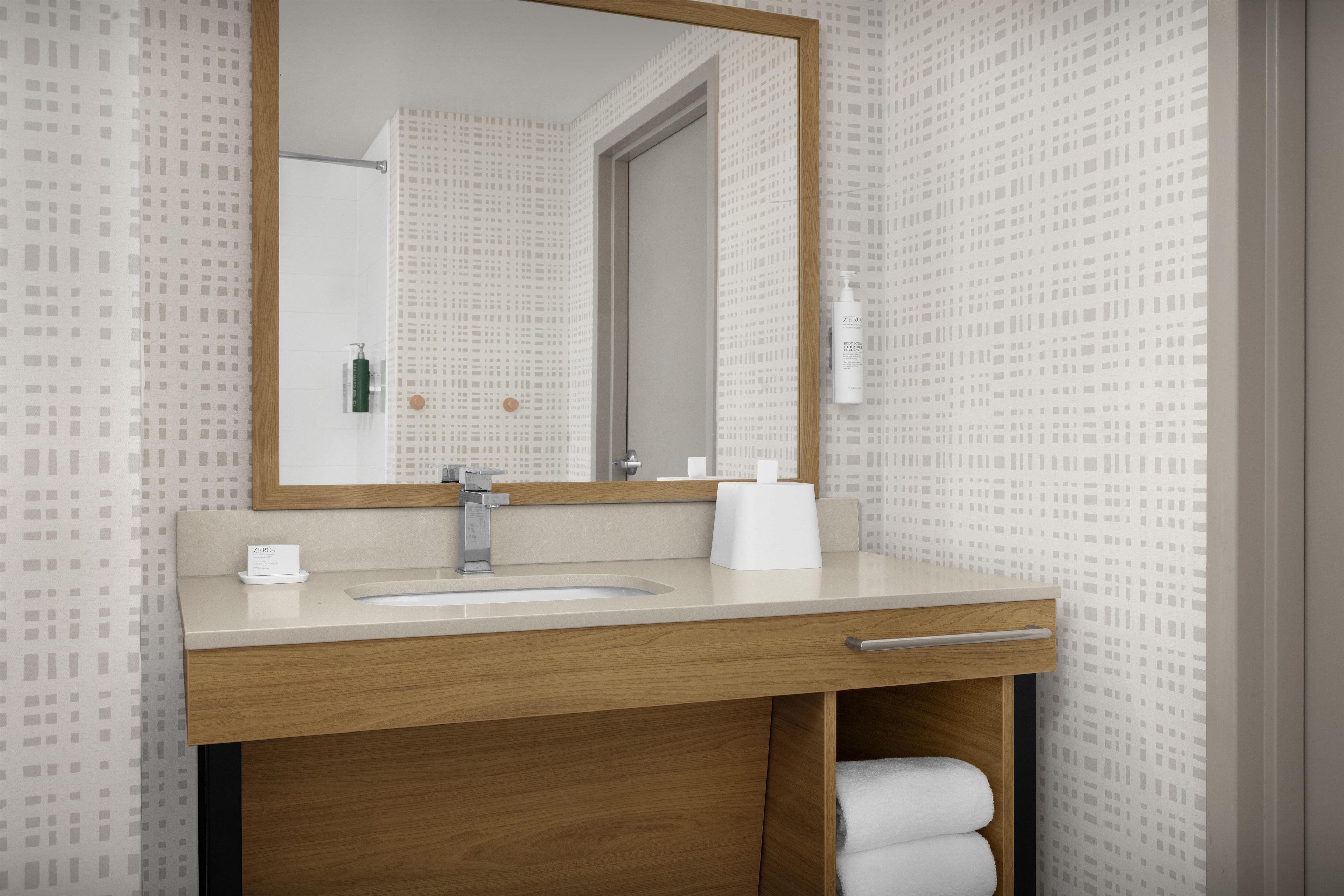 A bathroom with a wooden vanity, a sink, a mirror, and a towel rack.
