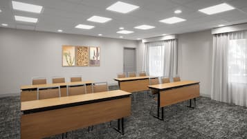 A conference room with long tables, chairs, and artwork on the wall.
