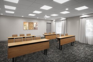 Ein Konferenzraum mit langen Tischen, Stühlen und Kunstwerken an der Wand.