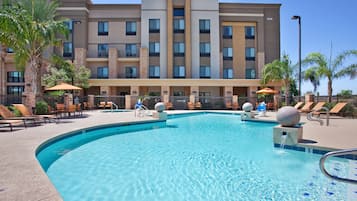 Een buitenzwembad, ligstoelen bij het zwembad