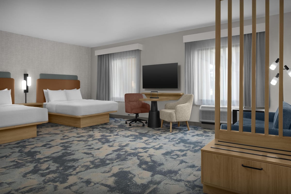 Ein Hotelzimmer mit zwei Betten, einem Schreibtisch, einem Fernseher und einer Minibar.