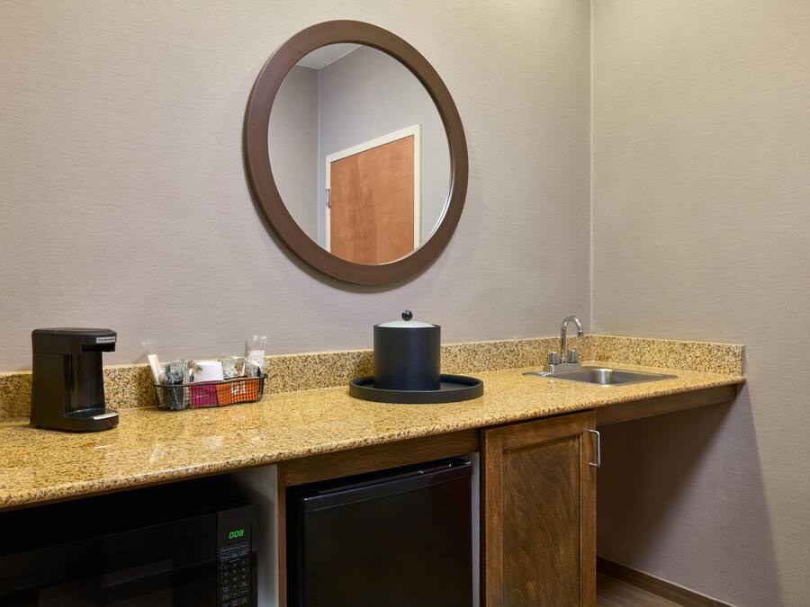 A kitchenette with a coffee maker, a microwave, a sink, and a small refrigerator.