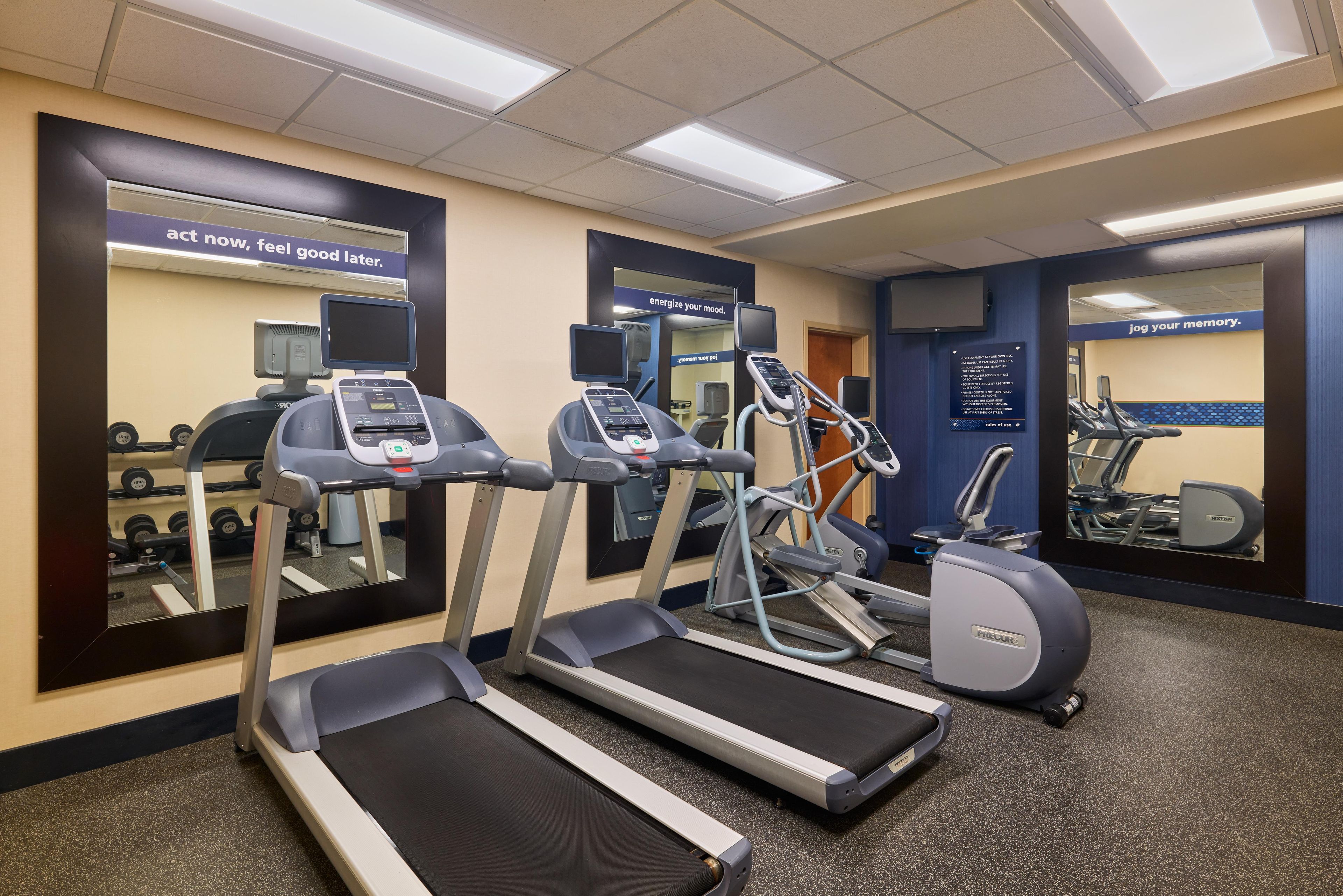 Un gimnasio con cintas de correr, elíptica y bicicleta estática.