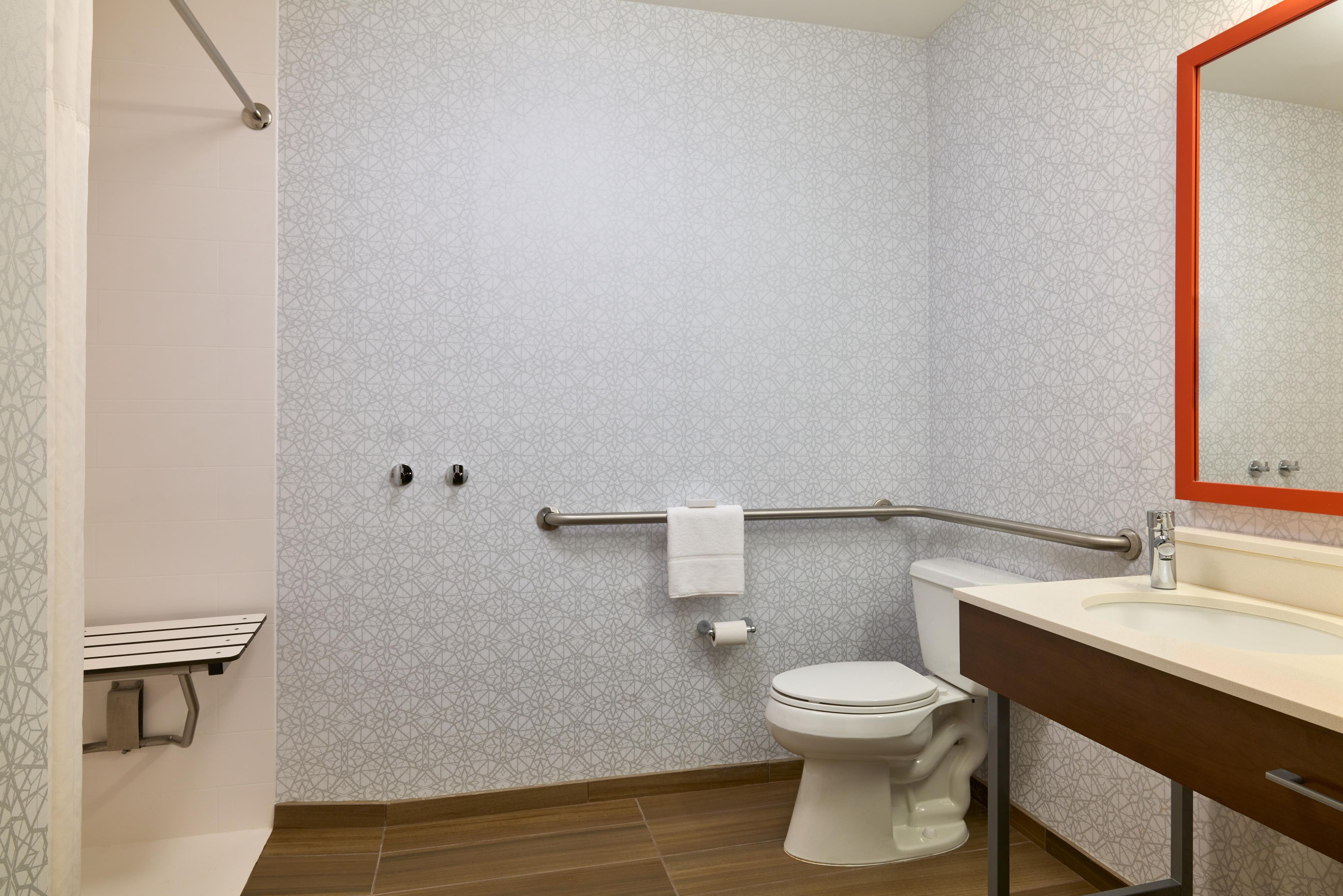 A bathroom with a toilet, a sink, a mirror, and a shower area.