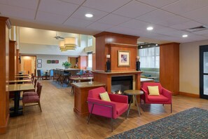 Un hall d’hôtel doté d’une cheminée, d’un coin salon et d’un espace repas.