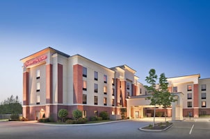 Un hotel Hampton Inn con un diseño moderno, que presenta fachada de ladrillo y un amplio estacionamiento.