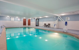 Una piscina interior con agua cristalina, un vestuario y una silla para socorrista.