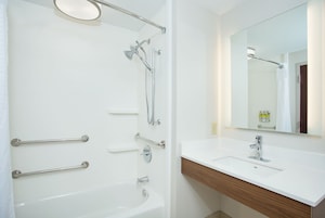 A modern bathroom with a bathtub, shower, and sink.