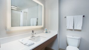 A modern bathroom with a white sink, mirror, and toilet.