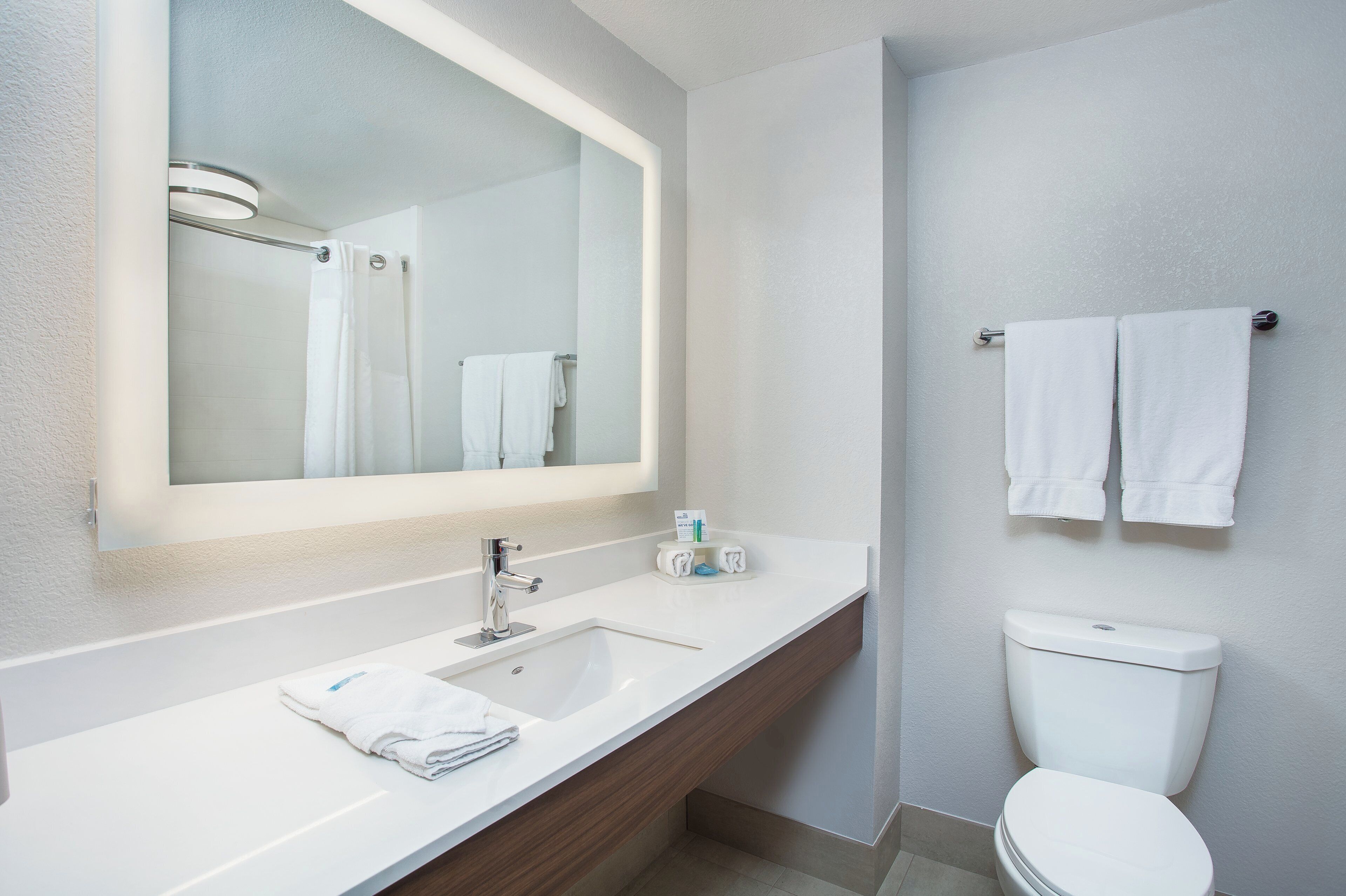 A modern bathroom with a white sink, mirror, and toilet.