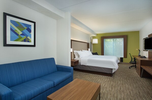 A hotel room with a blue sofa, a bed with white bedding, a desk with a computer, and a framed abstract artwork on the wall. - Holiday Inn Express & Suites Lebanon-Nashville Area by IHG (Lebanon)
