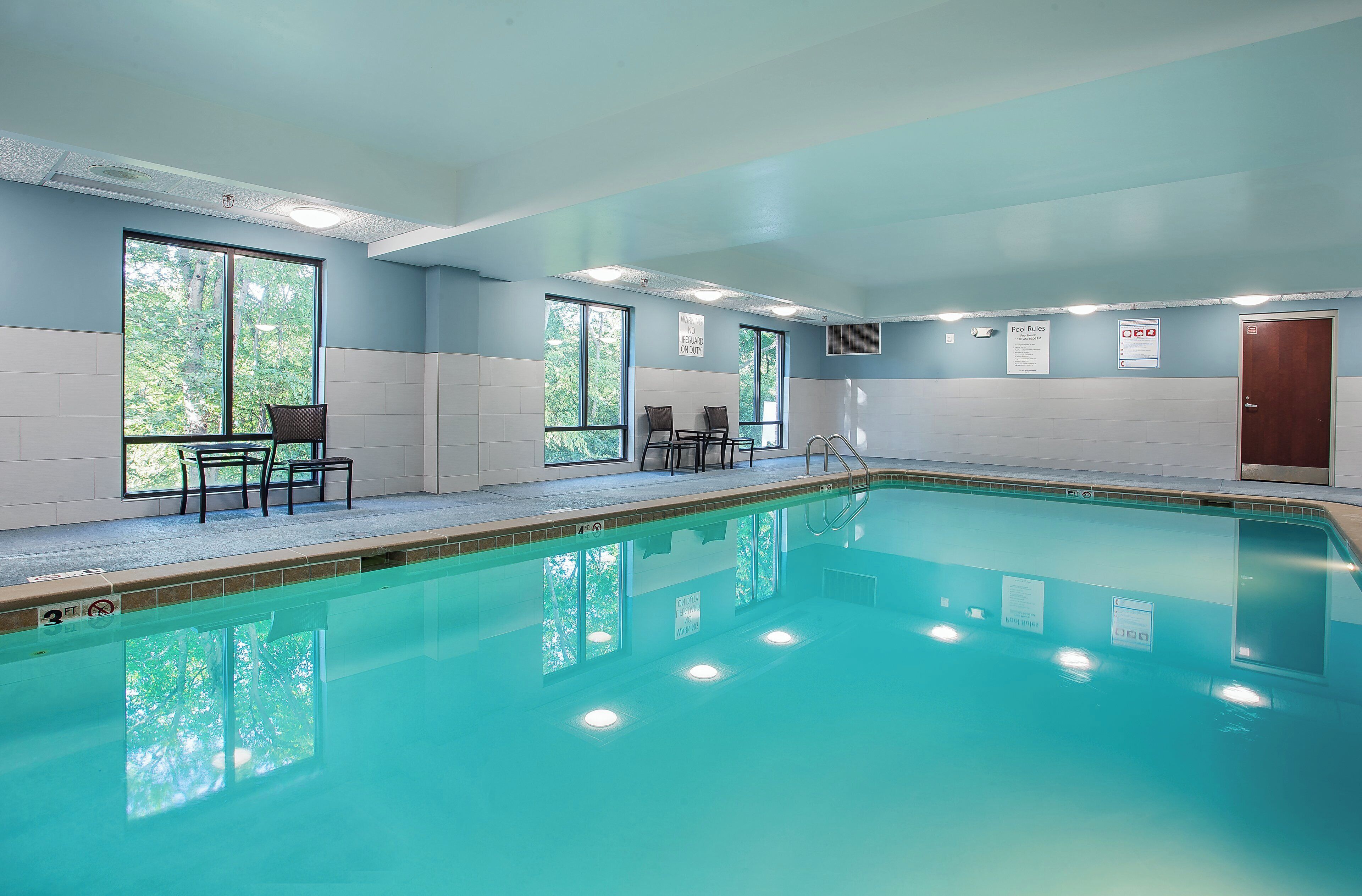 An indoor swimming pool with clear water, a lifeguard station, and seating areas.