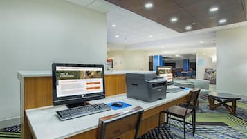Un mostrador de recepción de hotel con computadora, impresora y zona de estar.