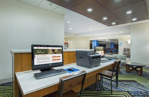 A hotel reception desk with a computer, printer, and seating area.