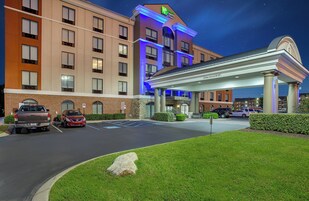 Un hotel Holiday Inn Express con estacionamiento, entrada cubierta y fachada de ladrillo.