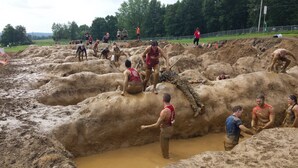 A muddy outdoor area with people engaged in a mud-related activity.