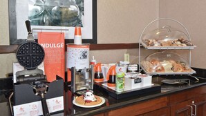 A breakfast buffet with waffle irons, a waffle maker, syrup dispensers, and a variety of pastries. - Hampton Inn & Suites Alexandria (Alexandria)