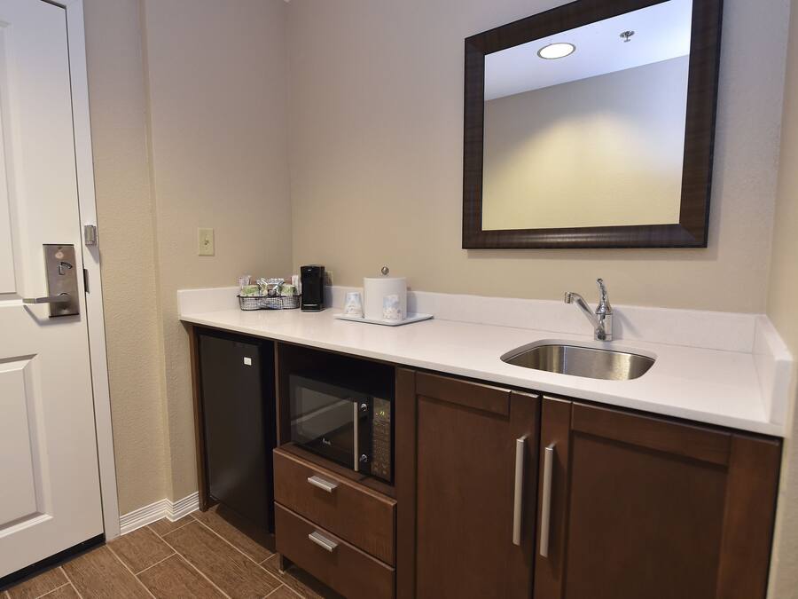 A compact kitchen with a built-in microwave, a sink, and a small countertop.