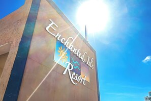 A sign for Enchanted Isle Resort with a clear sky in the background. - Enchanted Isle Resort (Hollywood)